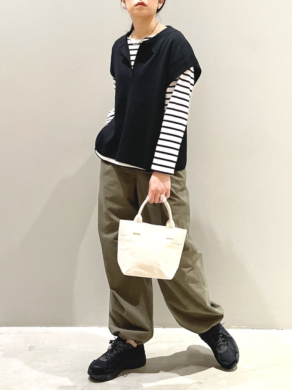 ブラック系のスニーカー、グリーン系のカーゴパンツ、ホワイト系のトートバッグを着用したレディースの秋コーディネートの4枚目の写真