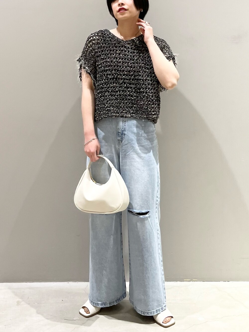 ブルー系のデニムパンツ、ホワイト系のサンダル、ホワイト系のショルダーバッグを着用したレディースの春コーディネートの5枚目の写真