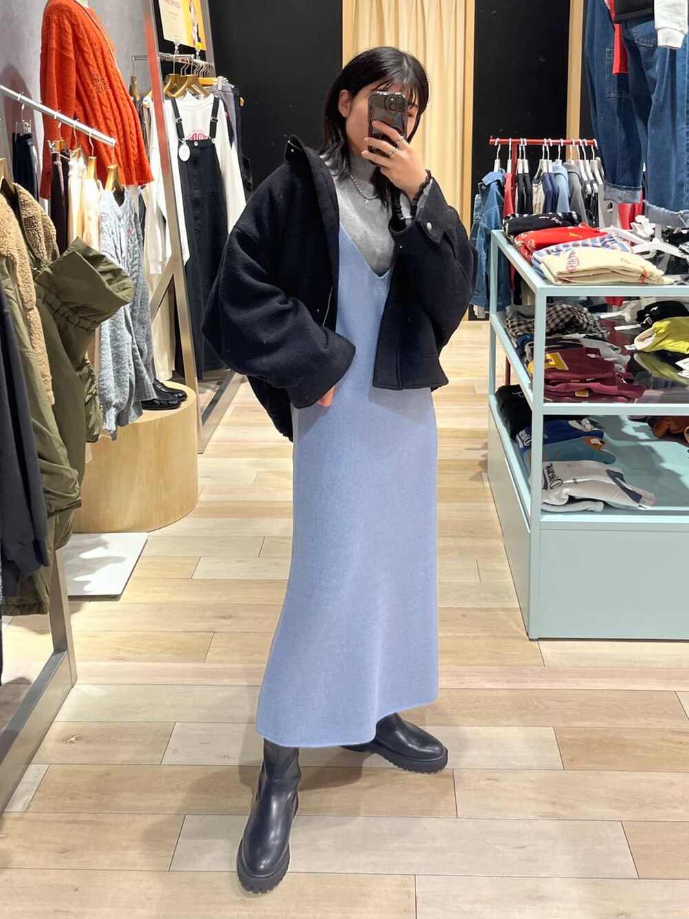 ブラック系のブルゾン、ブルー系のワンピース、ブラック系のブーツを着用したレディースの秋コーディネートの7枚目の写真