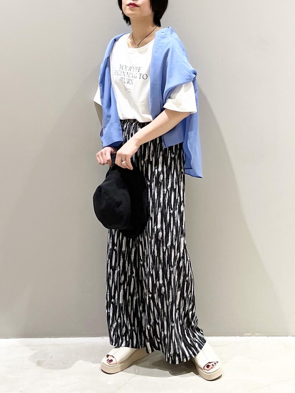 ブラック系のその他パンツ、ベージュ系のサンダル、ホワイト系のTシャツ/カットソーを着用したレディースの春コーディネートの3枚目の写真