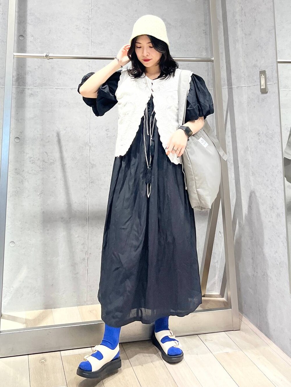 ブラック系のワンピース、ホワイト系のサンダル、ホワイト系のベストを着用したレディースの春コーディネートの4枚目の写真