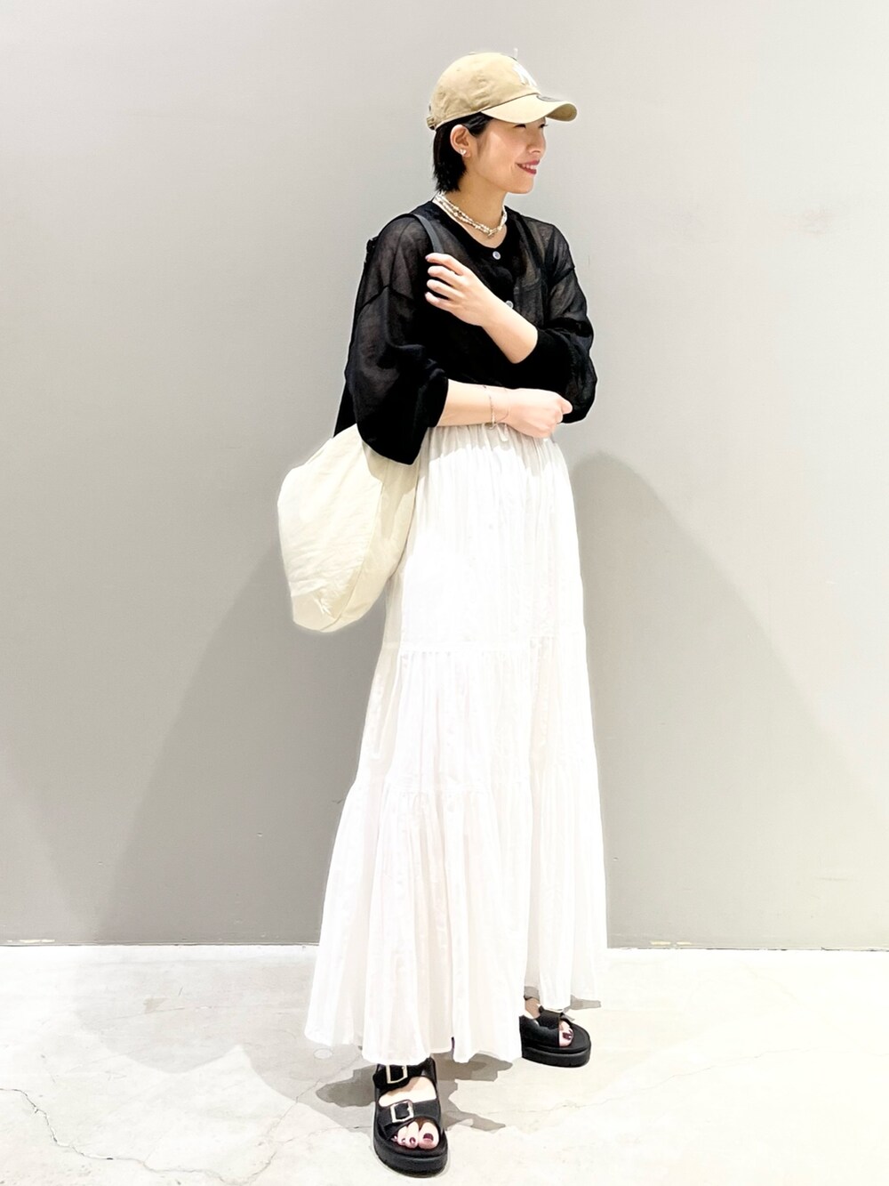 ブラック系のサンダル、ホワイト系のスカート、ホワイト系のショルダーバッグを着用したレディースの夏コーディネートの6枚目の写真