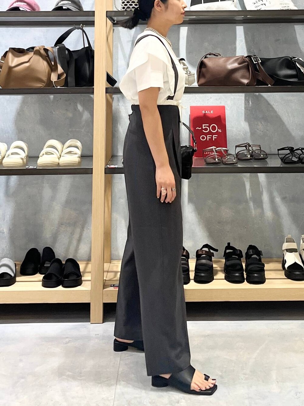 ブラック系のハンドバッグ、ブラック系のサンダル、ホワイト系のTシャツ/カットソーを着用したレディースの夏コーディネートの2枚目の写真