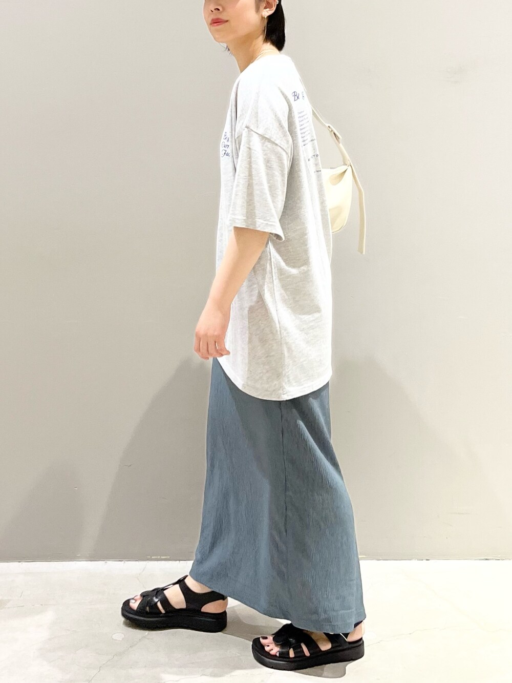 ホワイト系のショルダーバッグ、グリーン系のスカート、ブラック系のシューズを着用したレディースの夏コーディネートの2枚目の写真