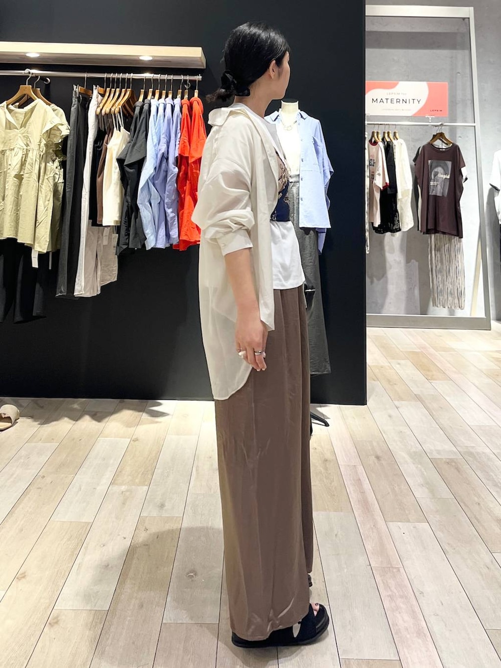 ブラック系のハンドバッグ、ブラック系のサンダル、ホワイト系のシャツ/ブラウスを着用したレディースの夏コーディネートの2枚目の写真