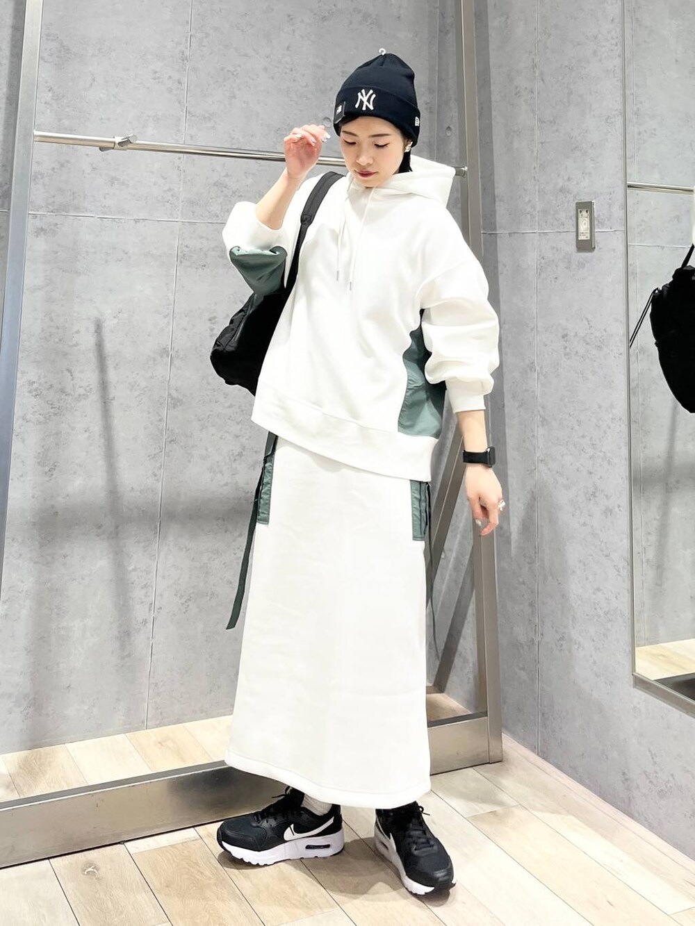ブラック系のショルダーバッグ、ホワイト系のスカート、ホワイト系のパーカーを着用したレディースの冬コーディネートの9枚目の写真