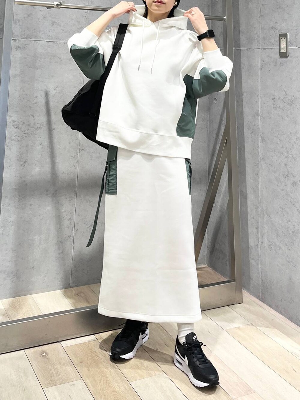 ブラック系のショルダーバッグ、ホワイト系のスカート、ホワイト系のパーカーを着用したレディースの冬コーディネートの2枚目の写真