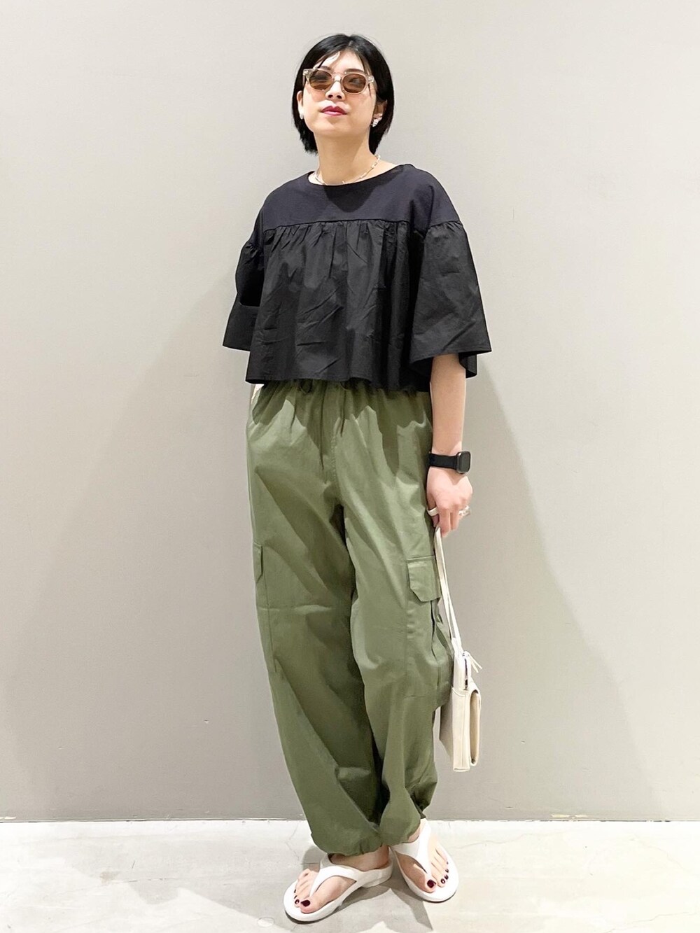 グリーン系のパンツ、ブラック系のTシャツ/カットソー、ホワイト系のショルダーバッグを着用したレディースの春コーディネートの4枚目の写真