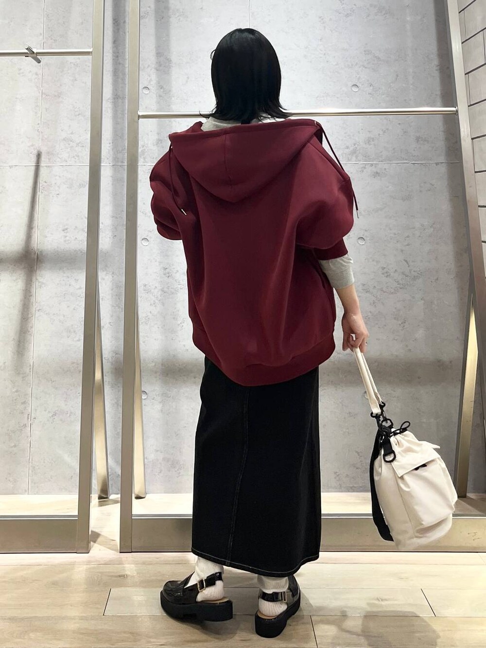 ホワイト系のショルダーバッグ、レッド系のパーカー、ブラック系のデニムスカートを着用したレディースの冬コーディネートの5枚目の写真