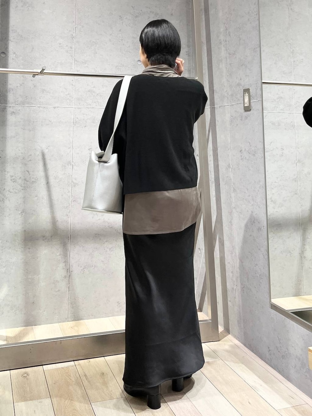 ブラック系のスカート、ブラック系のニット/セーター、グレー系のシャツ/ブラウスを着用したレディースの秋コーディネートの5枚目の写真