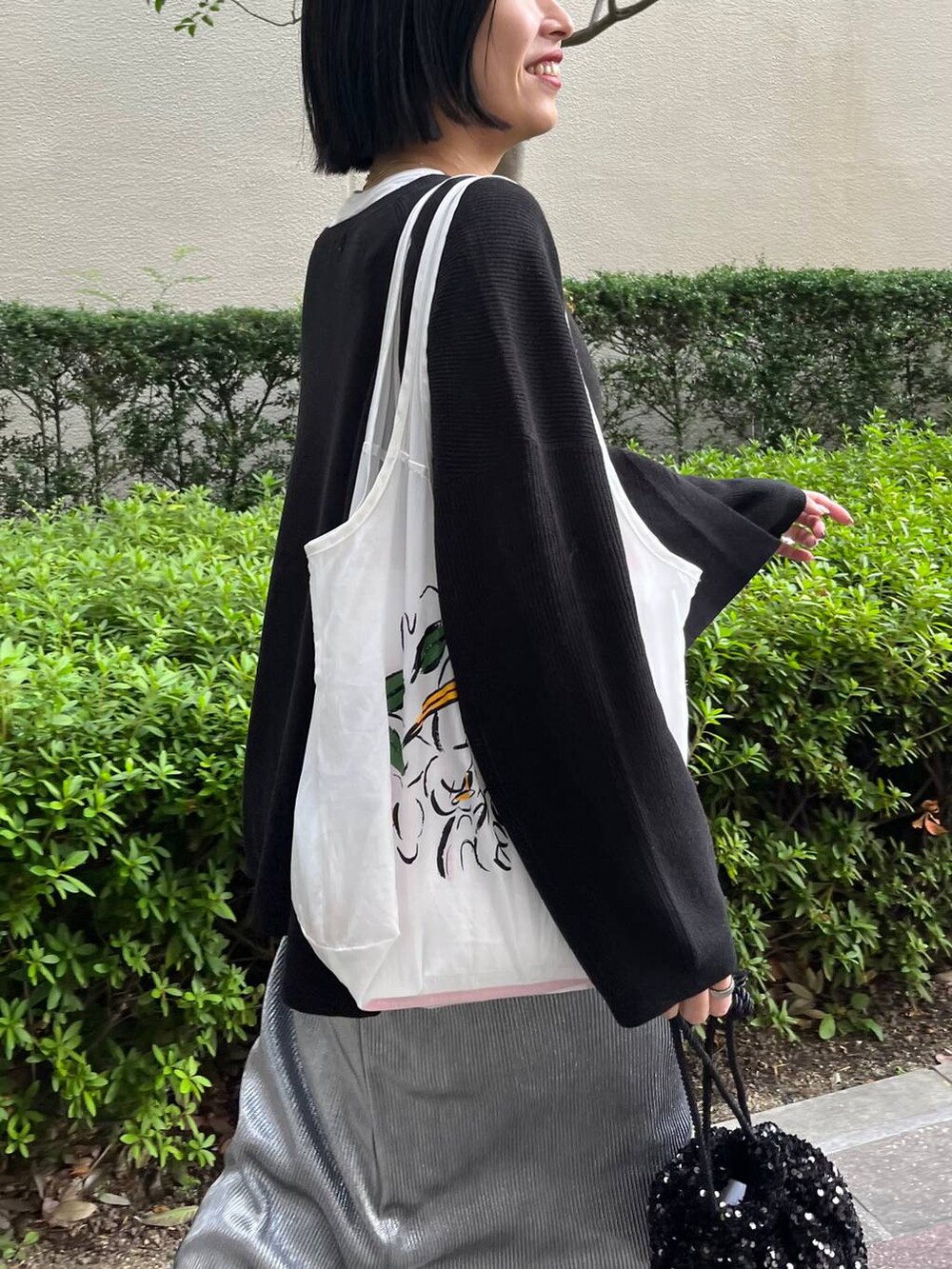 ブラック系のニット/セーター、ホワイト系のTシャツ/カットソー、シルバー系のスカートを着用したレディースの秋コーディネートの2枚目の写真