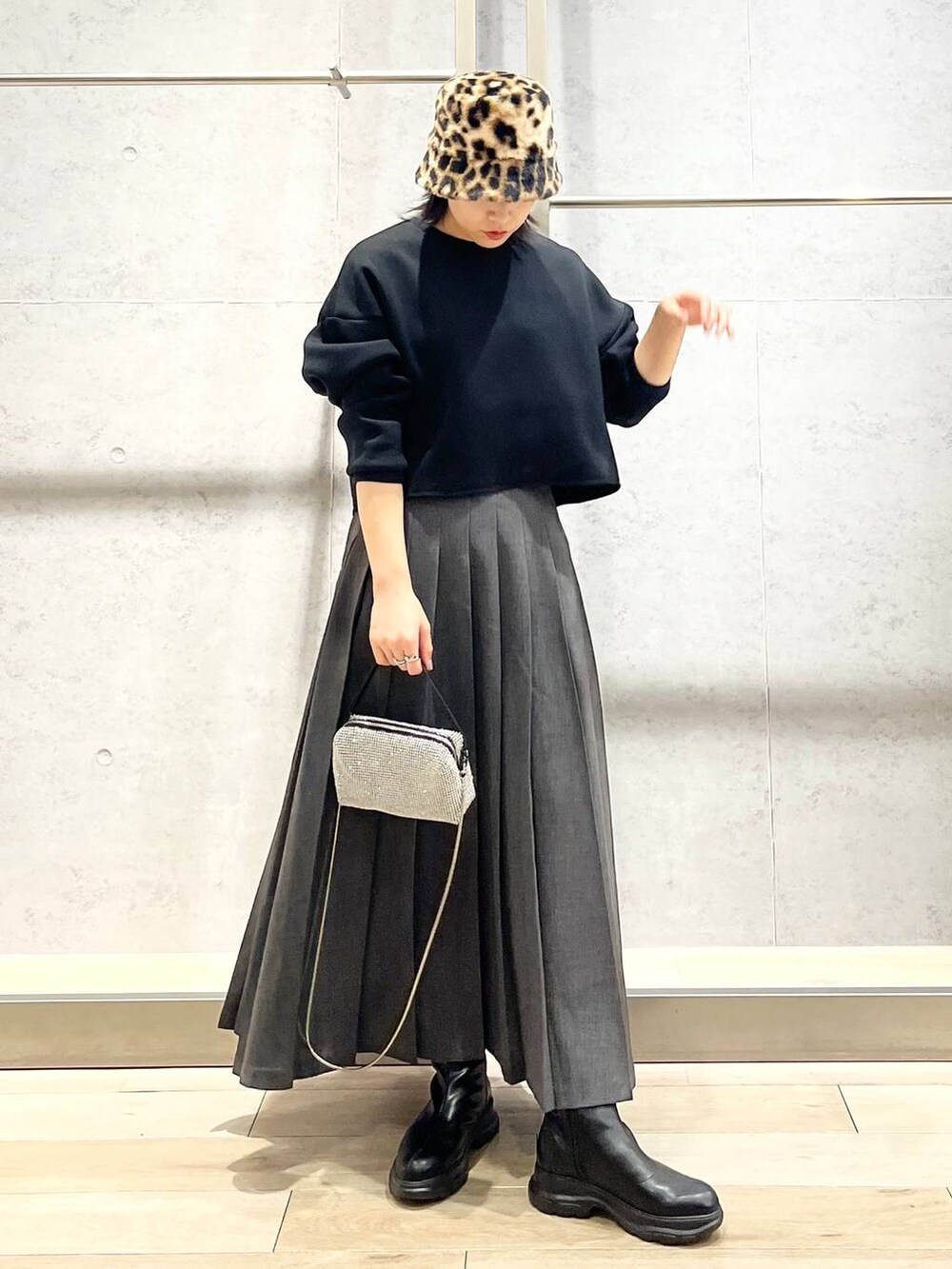 ブラック系のブーツ、ブラック系のTシャツ/カットソー、グレー系のスカートを着用したレディースの冬コーディネートの2枚目の写真