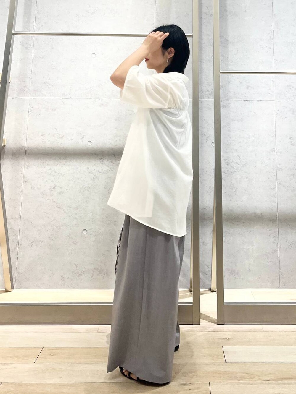 ブラック系のサンダル、ブラック系のハンドバッグ、グレー系のスラックスを着用したレディースの夏コーディネートの3枚目の写真