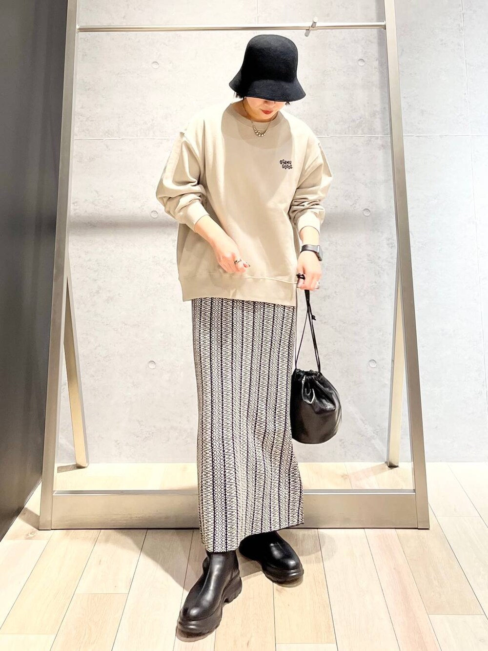 ブラック系のスカート、シルバー系のショルダーバッグ、ブラック系のブーツを着用したレディースの冬コーディネートの4枚目の写真