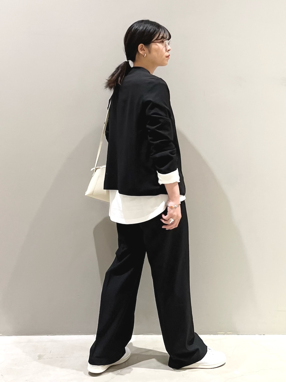 ブラック系のパンツ、ホワイト系のスニーカー、ホワイト系のショルダーバッグを着用したレディースの秋コーディネートの3枚目の写真