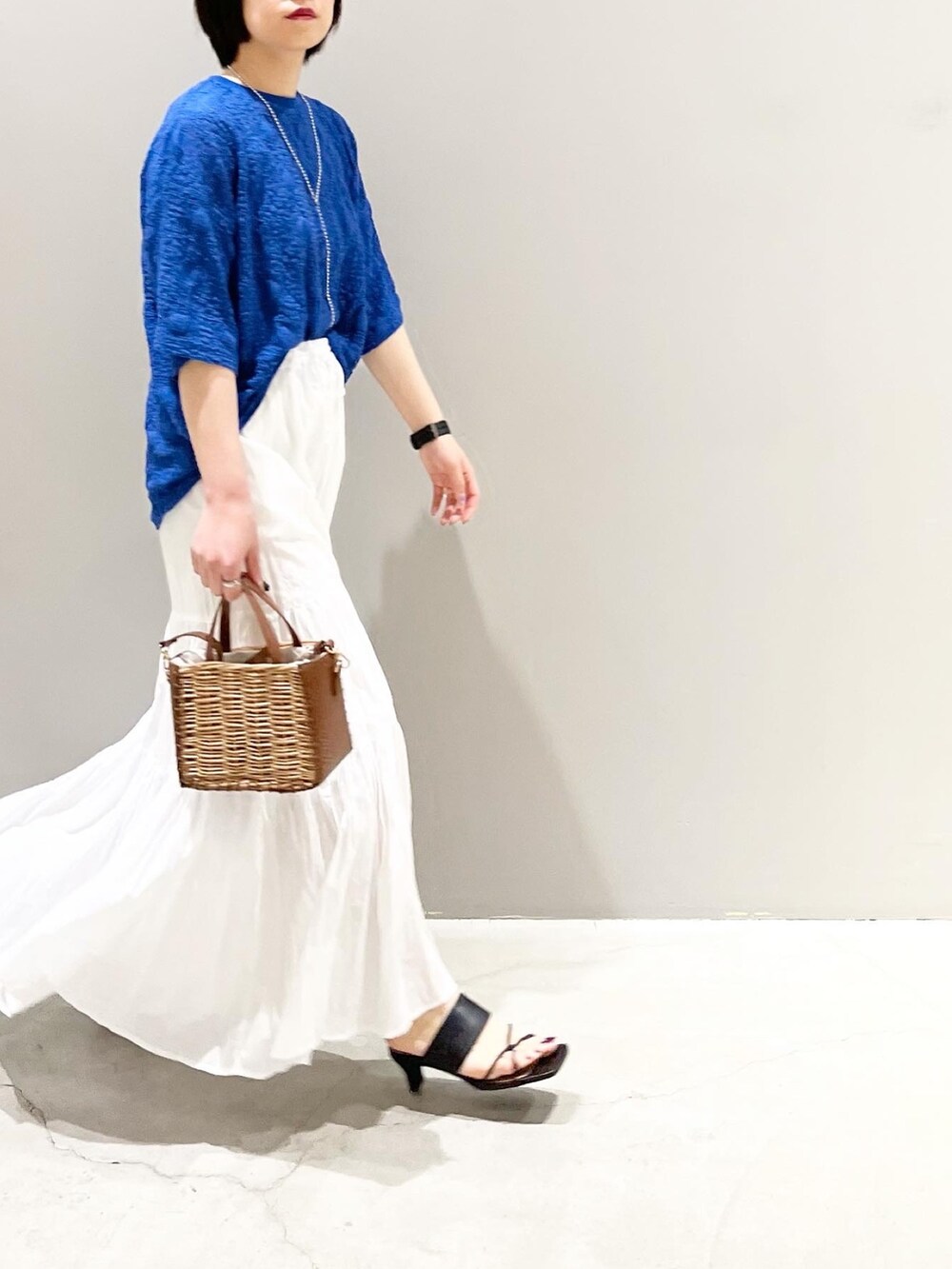 ブラック系のサンダル、ブラウン系のショルダーバッグ、ホワイト系のスカートを着用したレディースの夏コーディネートの6枚目の写真