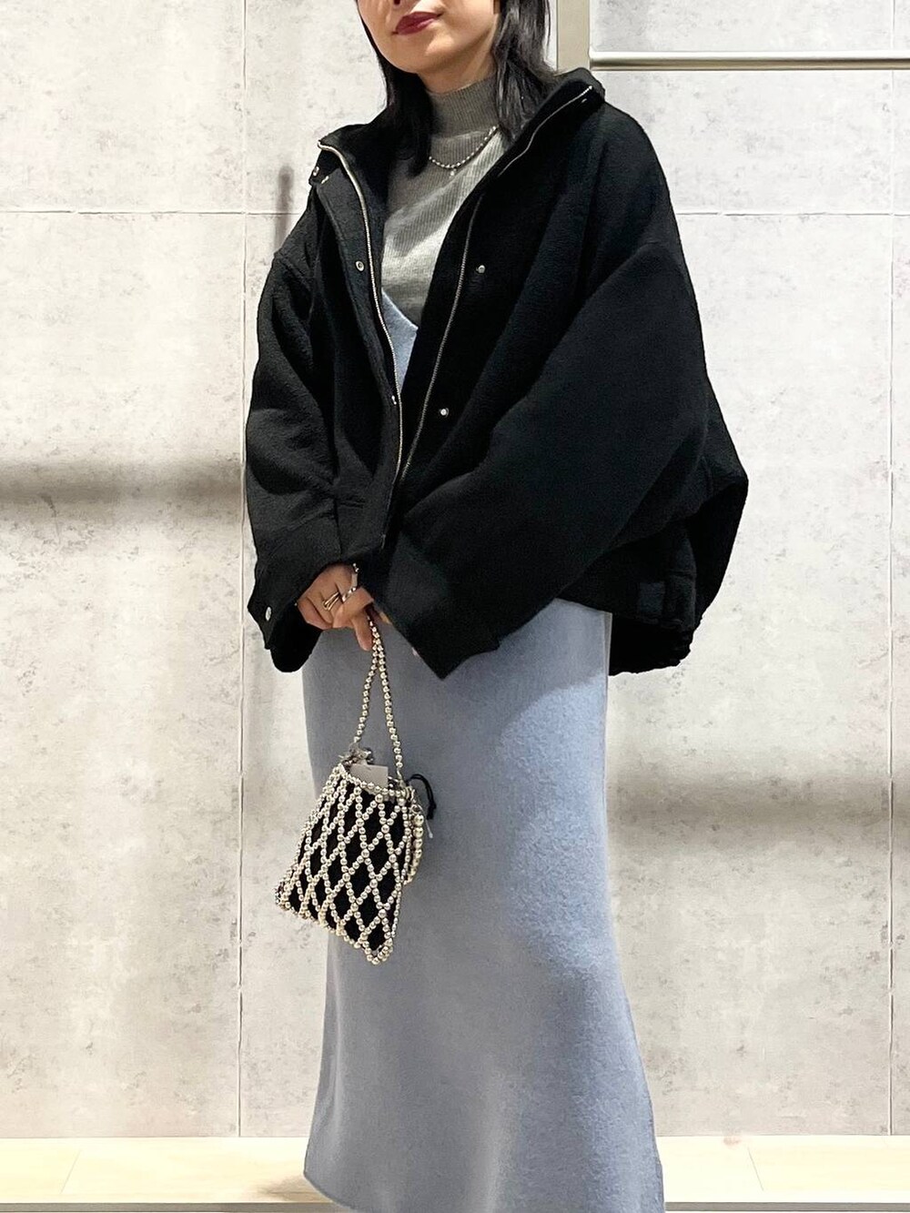 ブラック系のブルゾン、ブルー系のワンピース、ブラック系のブーツを着用したレディースの秋コーディネートの9枚目の写真