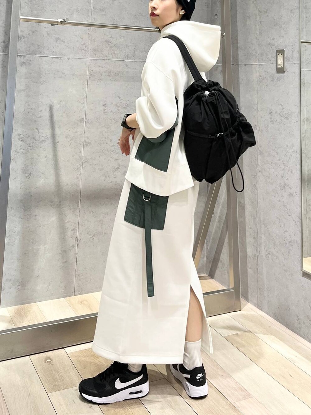 ブラック系のショルダーバッグ、ホワイト系のスカート、ホワイト系のパーカーを着用したレディースの冬コーディネートの7枚目の写真