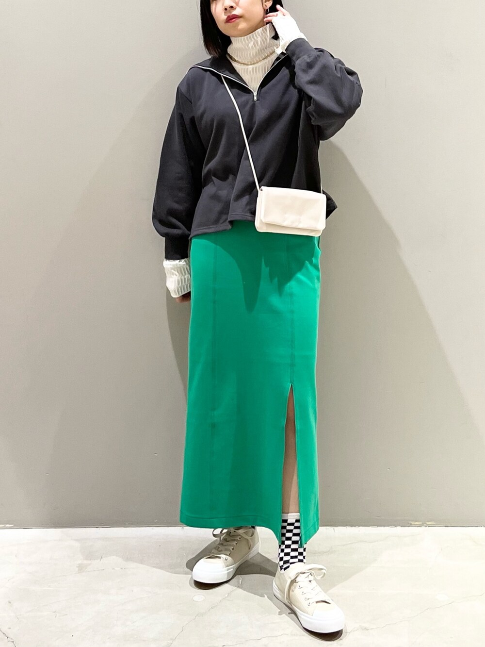 グリーン系のスカート、ベージュ系のスニーカー、ホワイト系のショルダーバッグを着用したレディースの春コーディネートの2枚目の写真