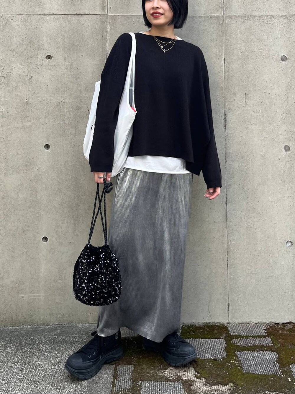 ブラック系のニット/セーター、ホワイト系のTシャツ/カットソー、シルバー系のスカートを着用したレディースの秋コーディネートの5枚目の写真