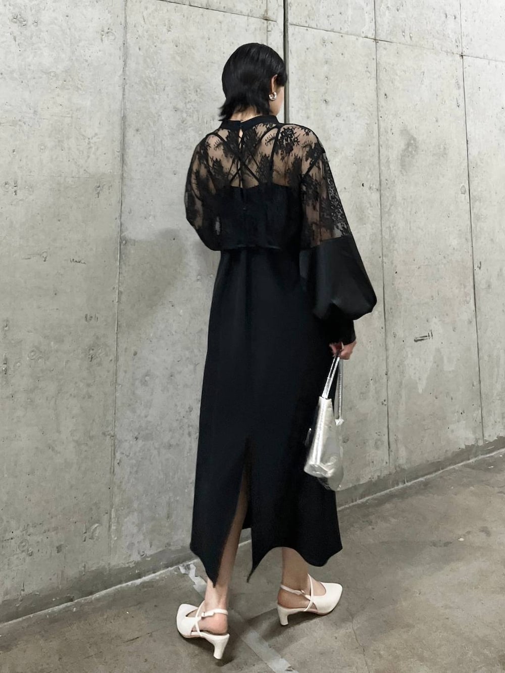 シルバー系のハンドバッグ、ホワイト系のパンプス、ゴールド系のネックレスを着用したレディースの春コーディネートの4枚目の写真