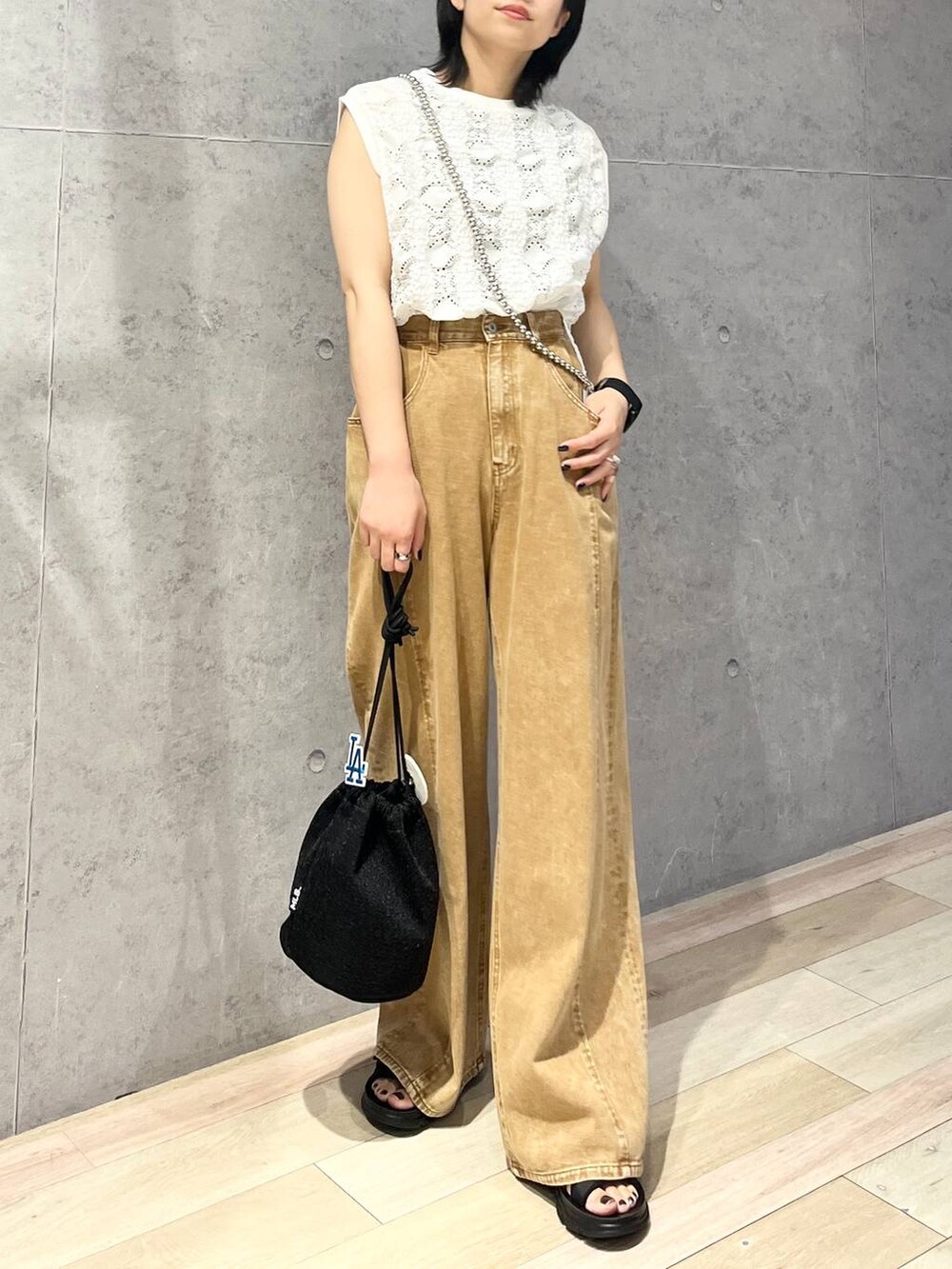 ブラック系のショルダーバッグ、ブラウン系のデニムパンツ、ブラック系のサンダルを着用したレディースの夏コーディネートの2枚目の写真