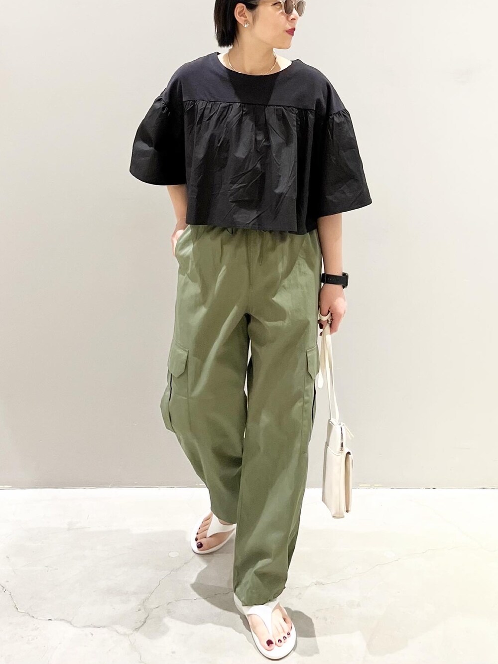 グリーン系のパンツ、ブラック系のTシャツ/カットソー、ホワイト系のショルダーバッグを着用したレディースの春コーディネートの2枚目の写真