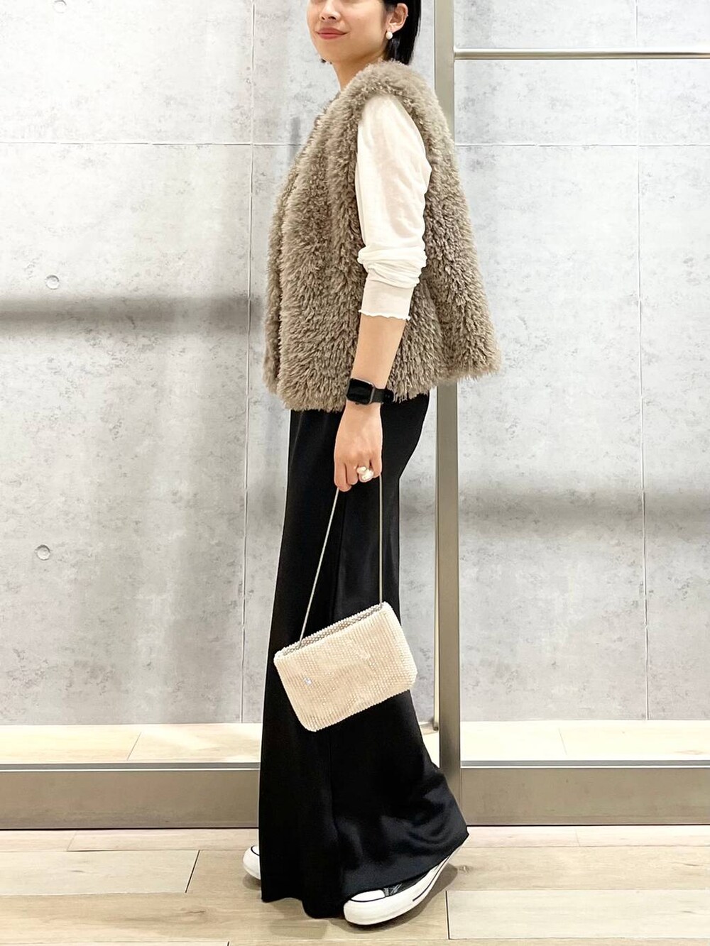 ブラック系のキャミソール、ベージュ系のベスト、ホワイト系のTシャツ/カットソーを着用したレディースの秋コーディネートの3枚目の写真