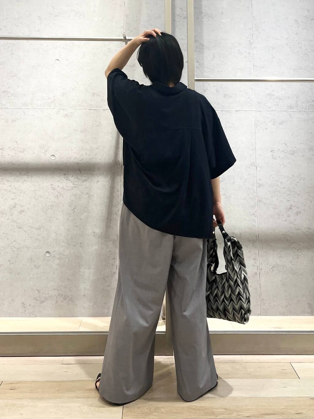 ブラック系のサンダル、ブラック系のハンドバッグ、ホワイト系のタンクトップを着用したレディースの夏コーディネートの5枚目の写真