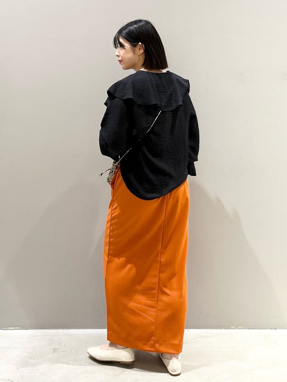 オレンジ系のスカート、ホワイト系のパンプス、その他のショルダーバッグを着用したレディースの春コーディネートの4枚目の写真