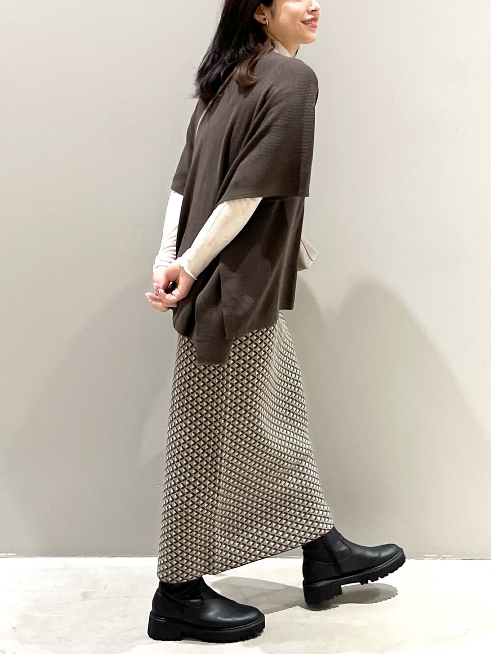 ブラウン系のスカート、ブラック系のブーツ、ブラウン系のニット/セーターを着用したレディースの秋コーディネートの2枚目の写真