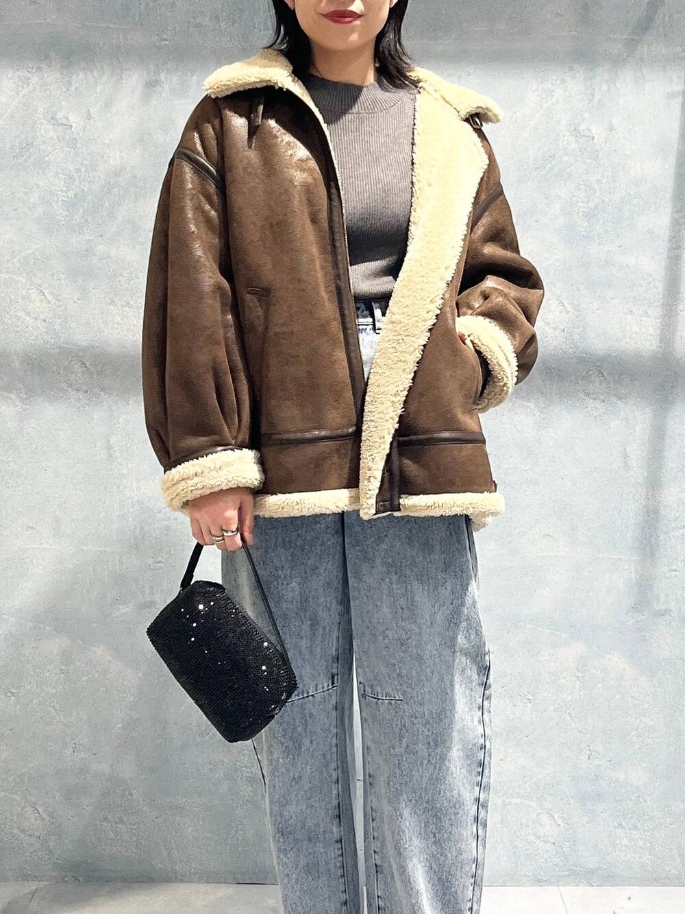 ブラウン系のその他アウター、ブラック系のブーツ、グレー系のニット/セーターを着用したレディースの秋コーディネートの2枚目の写真