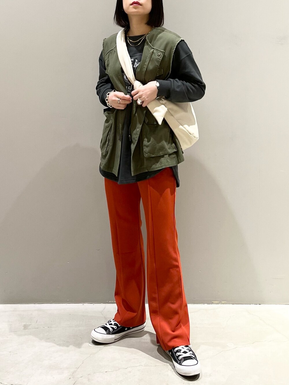 ブラック系のスニーカー、オレンジ系のその他パンツ、グリーン系のジャケット/アウターを着用したレディースの春コーディネートの5枚目の写真