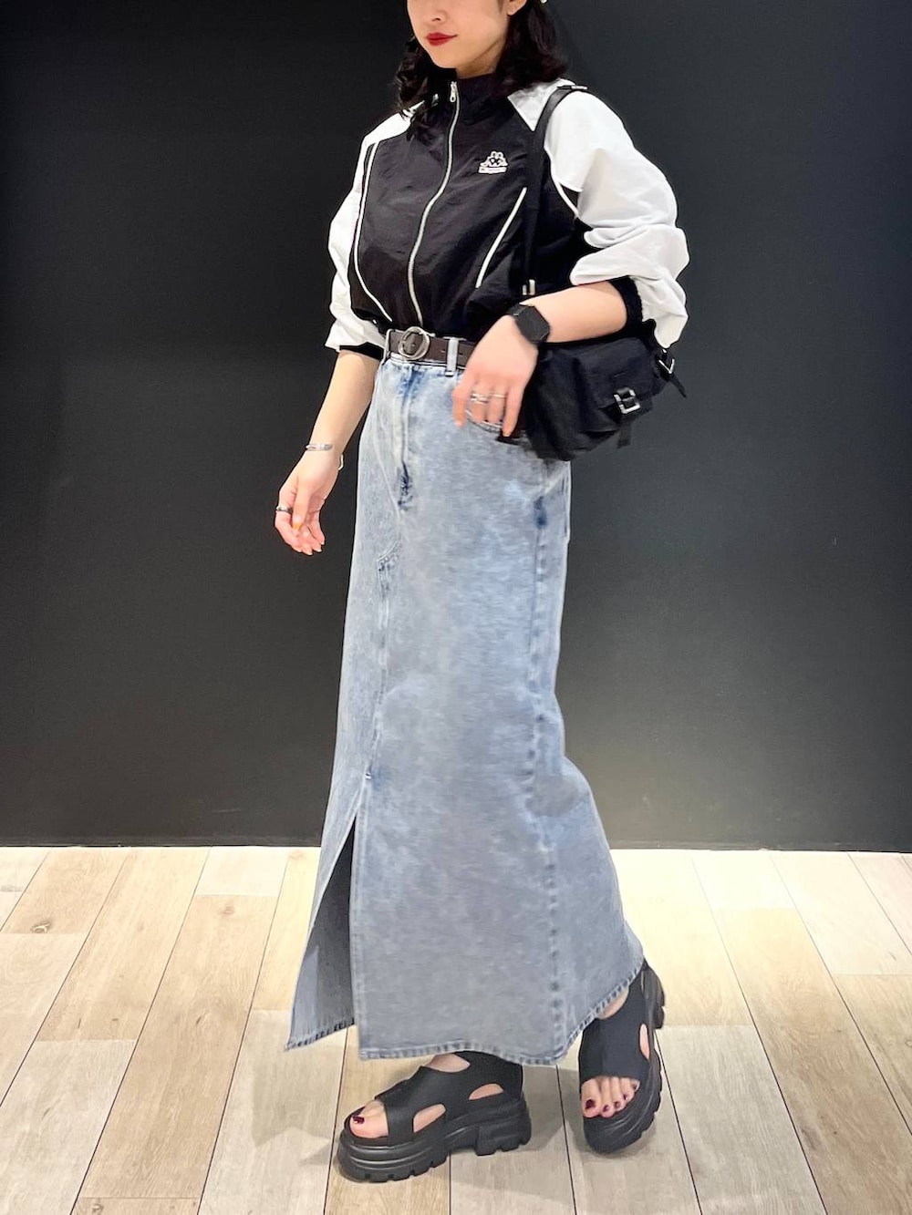 ブルー系のデニムスカート、ブラック系のショルダーバッグ、ブラック系のサンダルを着用したレディースの春コーディネートの2枚目の写真