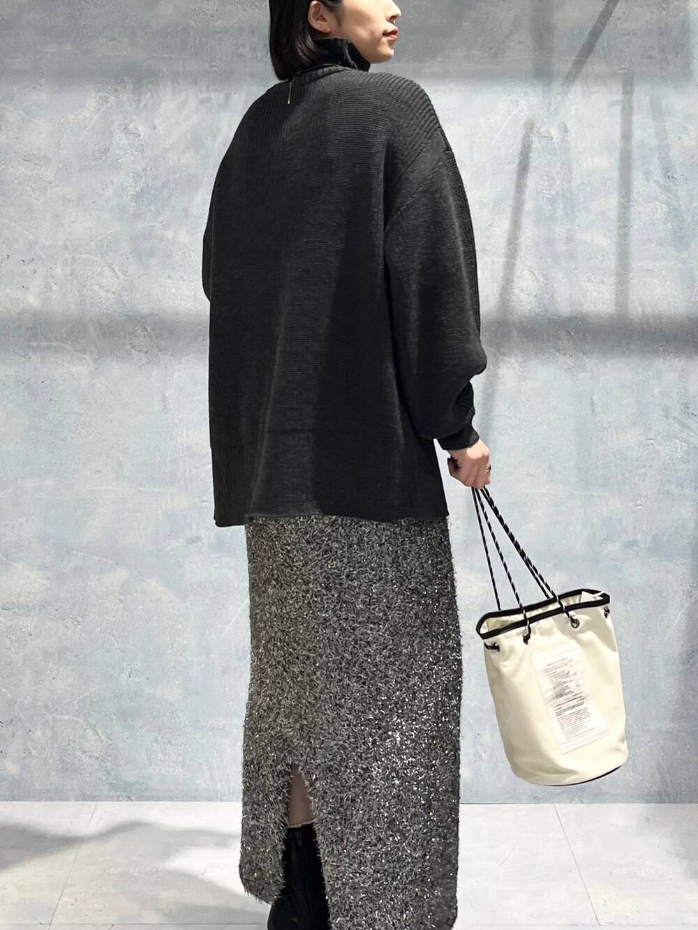 グレー系のTシャツ/カットソー、ブラック系のブーツ、ブラック系のスカートを着用したレディースの冬コーディネートの6枚目の写真