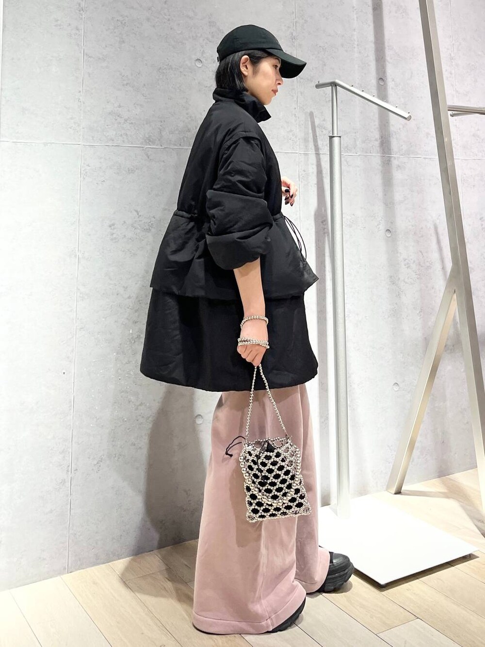 シルバー系のショルダーバッグ、ピンク系のスウェットパンツ、ブラック系のキャップを着用したレディースの秋コーディネートの3枚目の写真