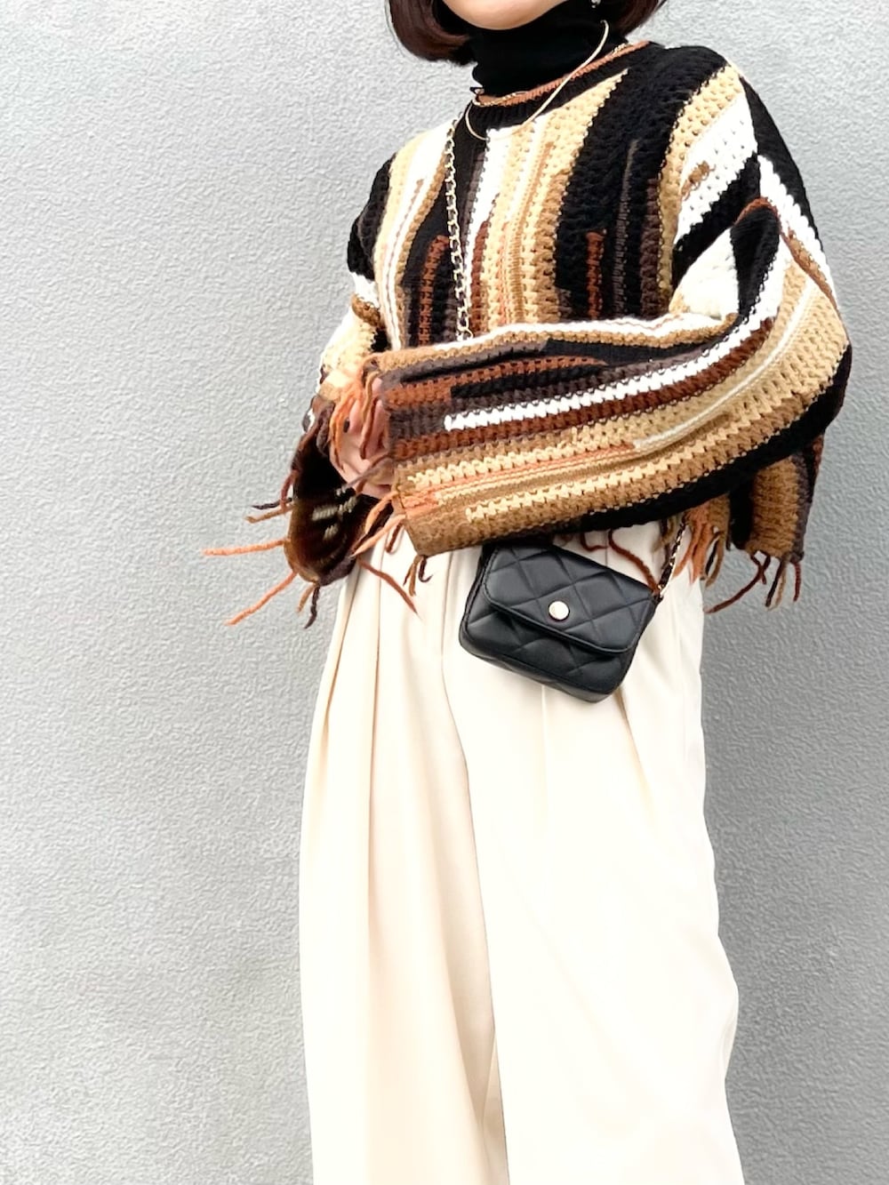 ブラック系のバッグ、ホワイト系のその他パンツ、ブラック系のブーツを着用したレディースの冬コーディネートの2枚目の写真