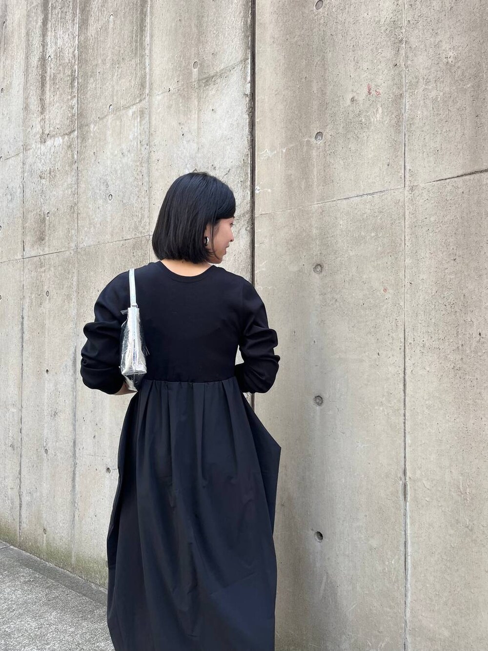 シルバー系のハンドバッグ、ブラック系のワンピース、グレー系のパンプスを着用したレディースの冬コーディネートの7枚目の写真