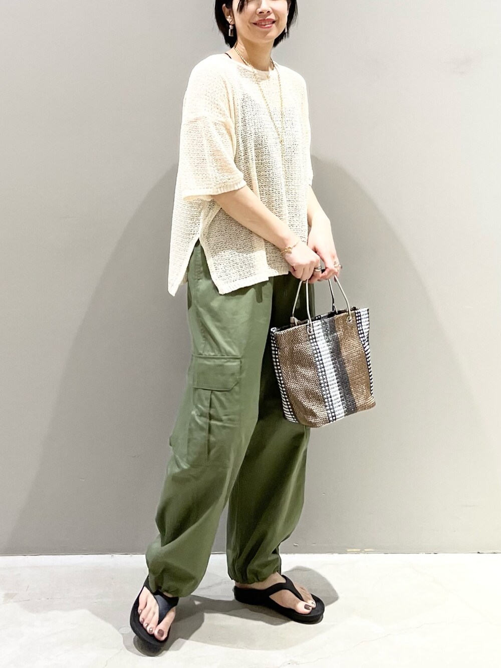 ブラック系のサンダル、ブラック系のトートバッグ、ホワイト系のニット/セーターを着用したレディースの夏コーディネートの9枚目の写真