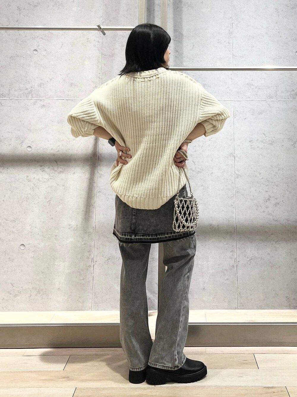 シルバー系のショルダーバッグ、ブラック系のデニムパンツ、ブラック系のブーツを着用したレディースの秋コーディネートの5枚目の写真