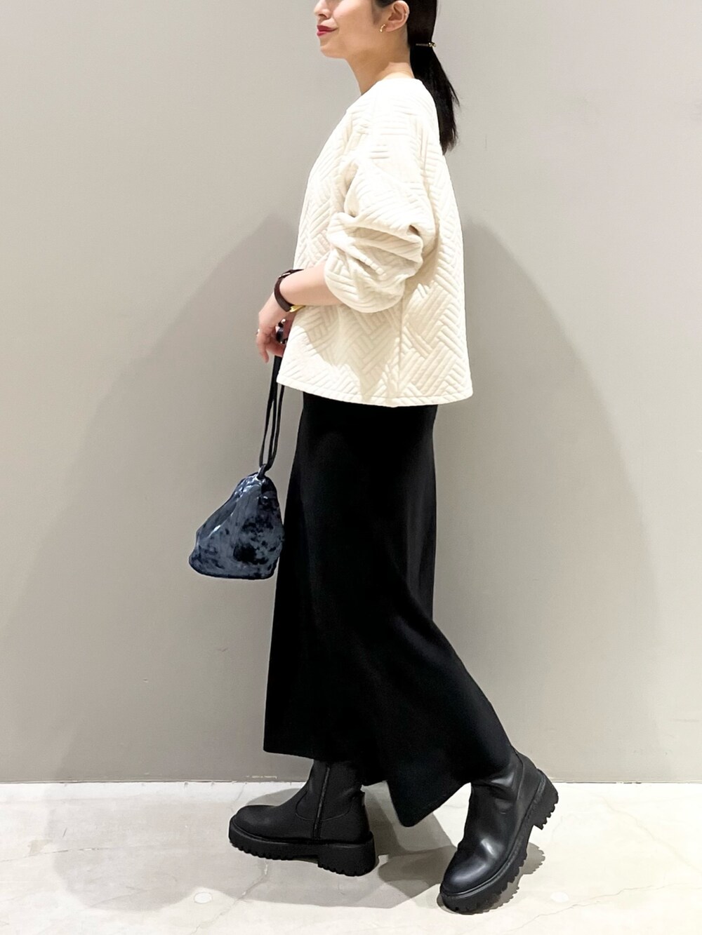 ブラック系のブーツ、ブラック系のスカート、ブルー系のショルダーバッグを着用したレディースの秋コーディネートの4枚目の写真