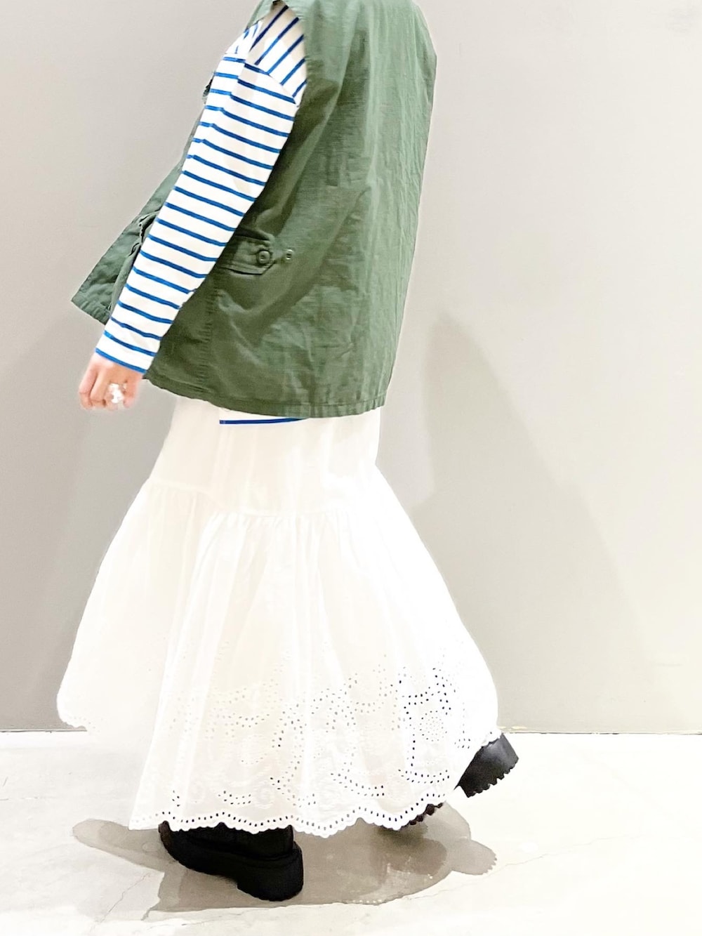 ブラック系のブーツ、ブルー系のTシャツ/カットソー、グリーン系のベストを着用したレディースの春コーディネートの3枚目の写真