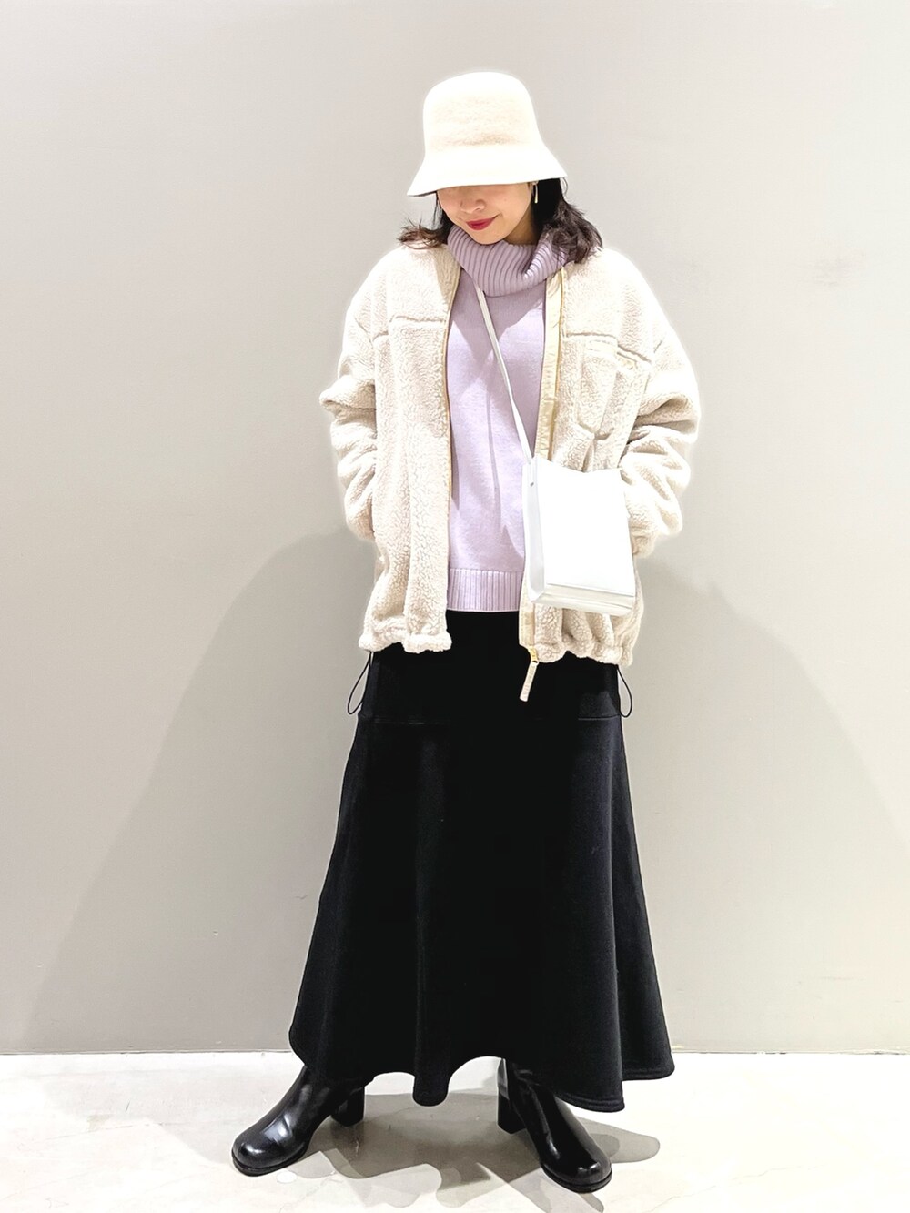 ブラック系のスカート、ブラック系のブーツ、ホワイト系のノーカラージャケットを着用したレディースの冬コーディネートの2枚目の写真