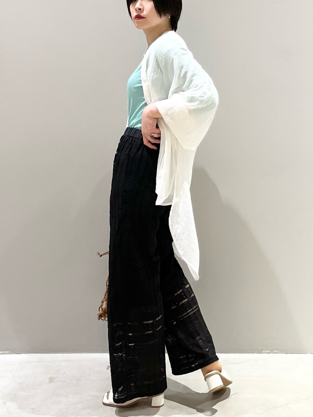 ブラック系のその他パンツ、ホワイト系のサンダル、ベージュ系のバッグを着用したレディースの春コーディネートの2枚目の写真