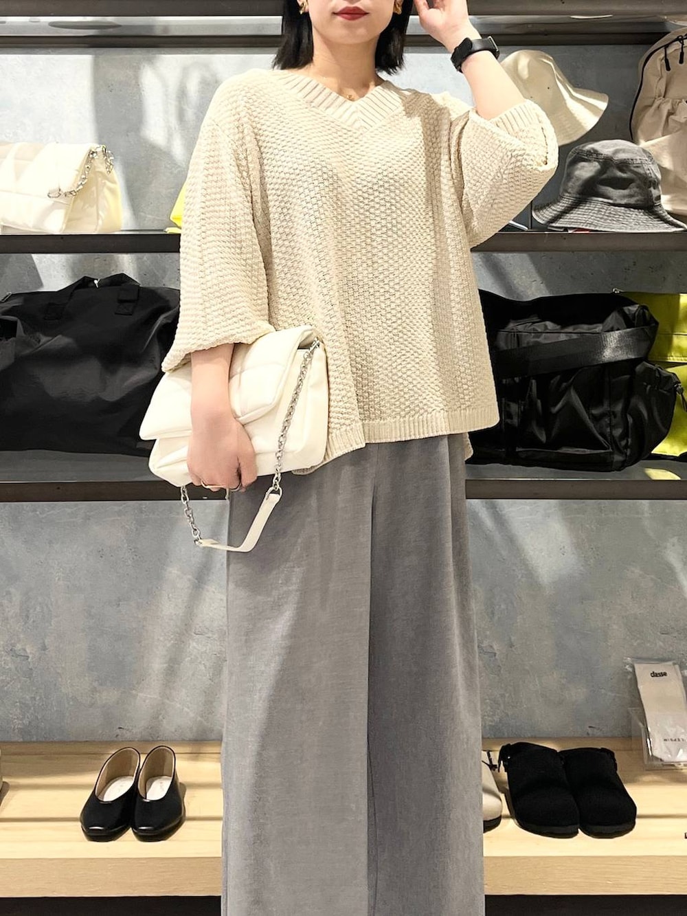 ホワイト系のショルダーバッグ、ホワイト系のニット/セーター、グレー系のスラックスを着用したレディースの春コーディネートの3枚目の写真