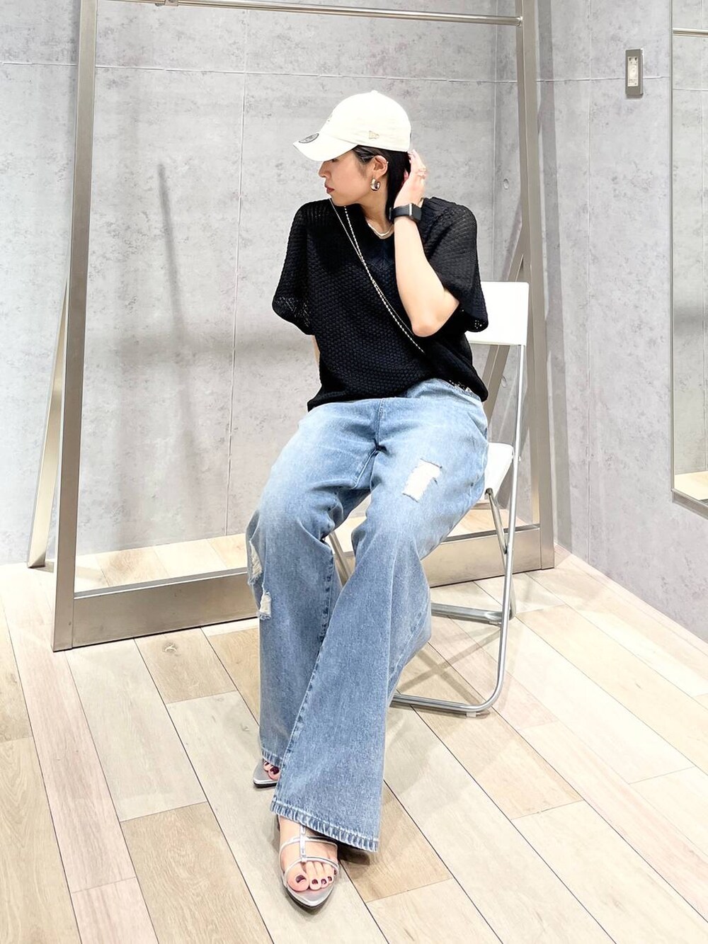 シルバー系のサンダル、ブラック系のニット/セーター、ブルー系のデニムパンツを着用したレディースの春コーディネートの2枚目の写真