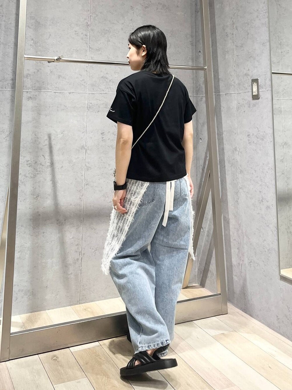 ブラック系のTシャツ/カットソー、ブラック系のサンダル、ブルー系のデニムパンツを着用したレディースの夏コーディネートの3枚目の写真