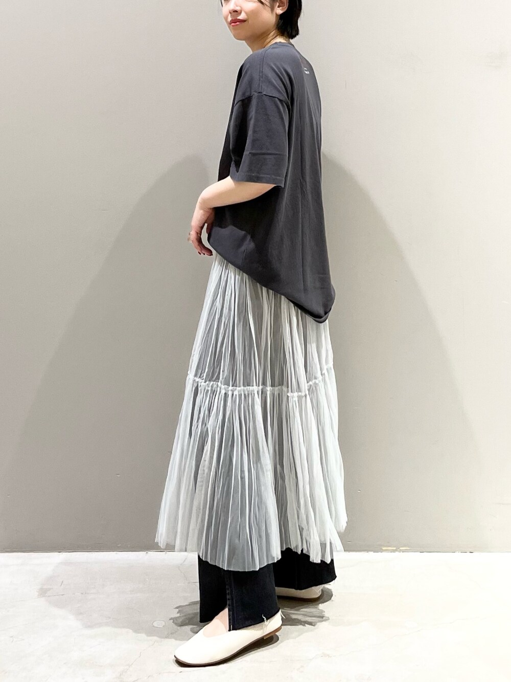 ブラック系のデニムパンツ、グレー系のスカート、ゴールド系のハンドバッグを着用したレディースの夏コーディネートの5枚目の写真