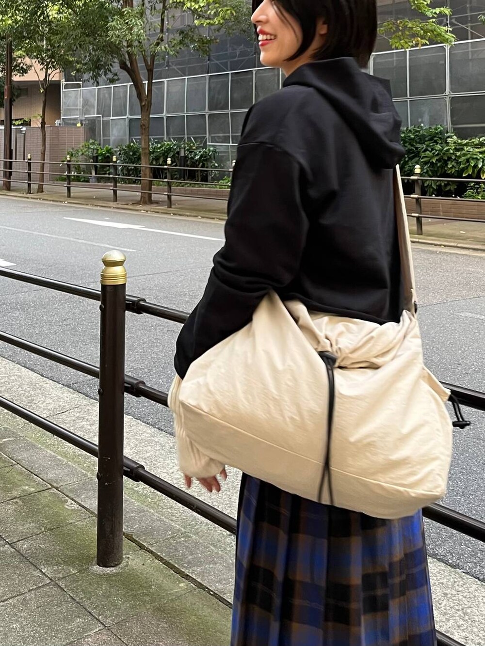 ブラック系のパーカー、ブルー系のスカート、ホワイト系のショルダーバッグを着用したレディースの秋コーディネートの5枚目の写真