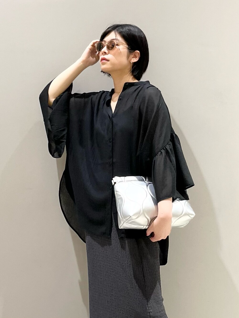 ベージュ系のサンダル、グレー系のスカート、グレー系のクラッチバッグを着用したレディースの夏コーディネートの6枚目の写真